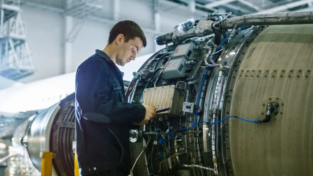 Engineer inspecting a jet engine in a hangar