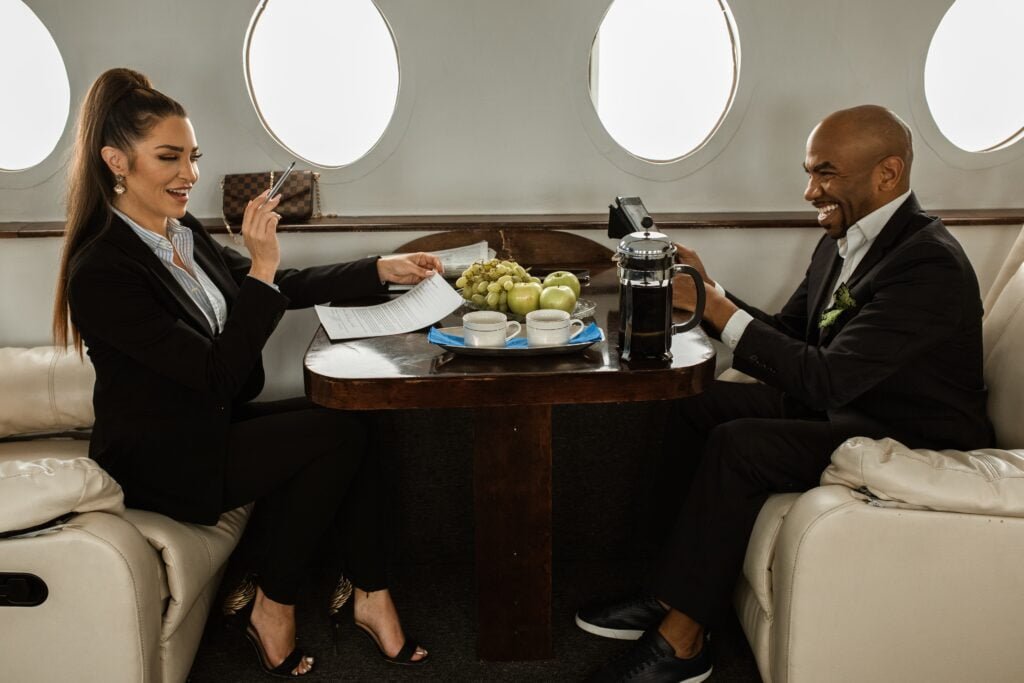 Two business travelers reviewing papers over coffee in a private jet cabin